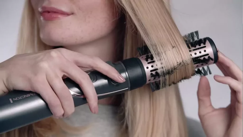 Mulher secando esticando o cabelo com escova rotativa