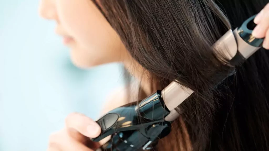Mulher criando ondas no cabelo com modelador de cachos